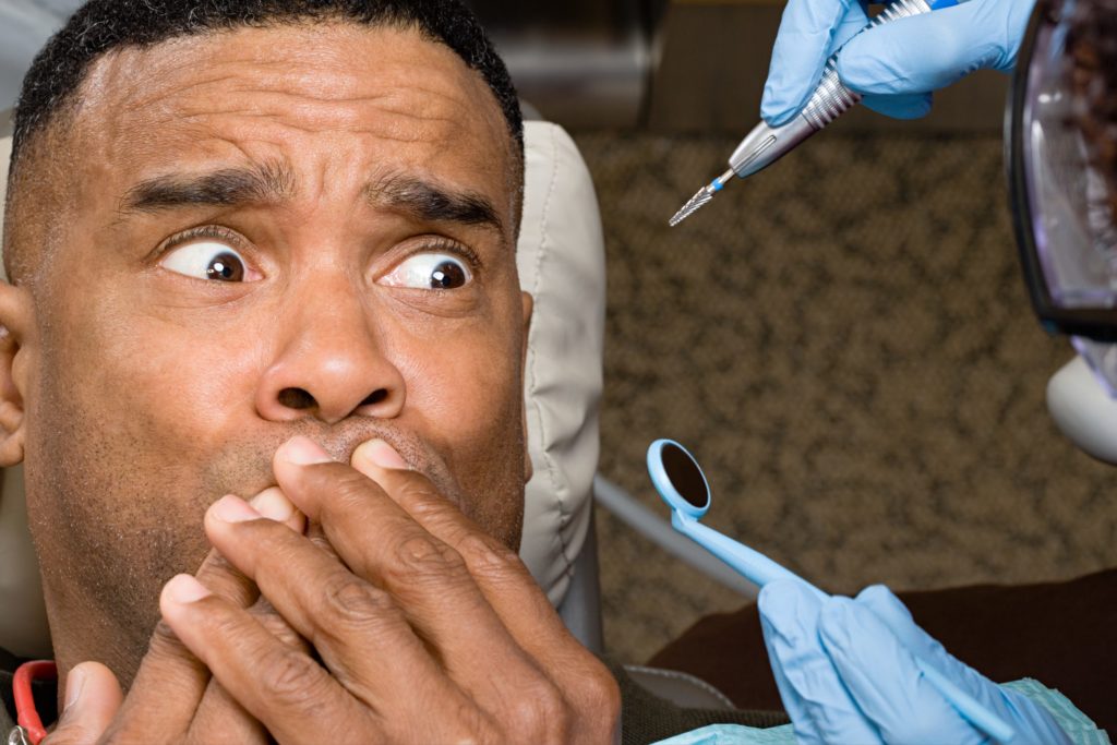 man holding mouth with dental implements near him